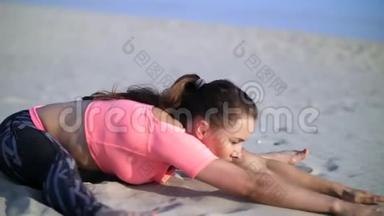 健康，年轻的美女伸展身体，在日出的时候在海滩上练习瑜伽，为平衡和平衡做运动